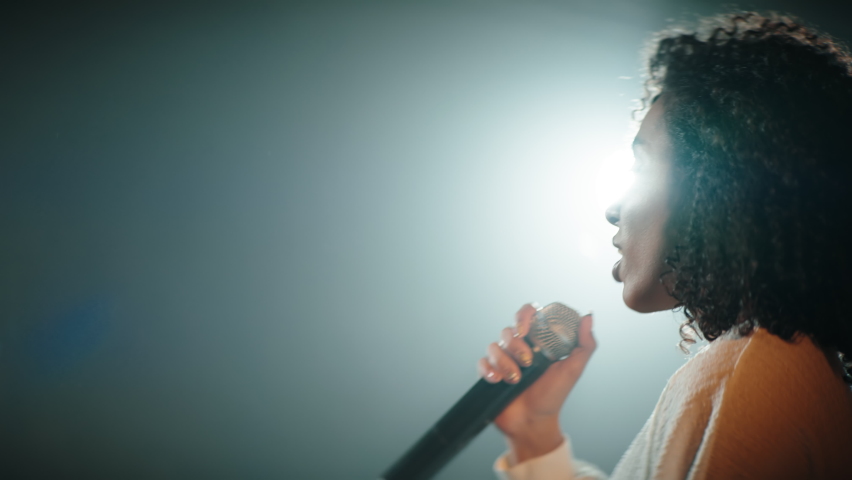CU Portrait of Black African American young female comedian performing her stand-up monologue on a stage of a small venue. Shot with ARRI Alexa Mini LF with 2x anamorphic lens Royalty-Free Stock Footage #1073129732