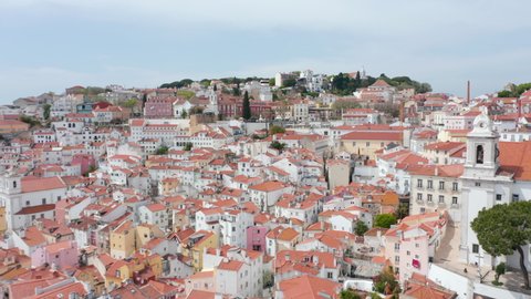 Aerial wide dolly out view of dense city center of colorful traditional old houses on the hills in Lisbon, Portugal
