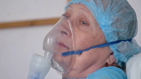 Portrait of old woman in oxygen mask on hospital bed
