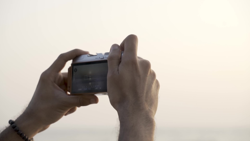 Serious Man Looking On LCD Screen Of His Camera While Capturing Scenic View. - Close Up, Selective Focus