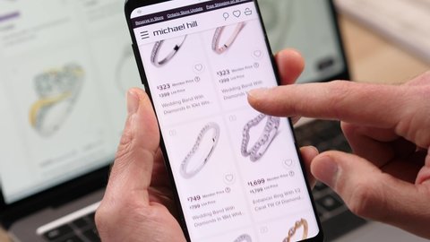 Shopping online using a mobile phone an engagement ring for a marriage. Looking at different rings of different shapes and prices MONTREAL CANADA MAY 2021