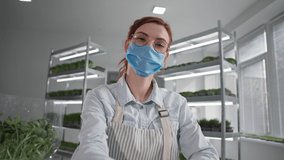 online trade, successful business woman grows microgreen in a greenhouse and sells offline via video link on laptop while talking with customer sitting on background of shelves