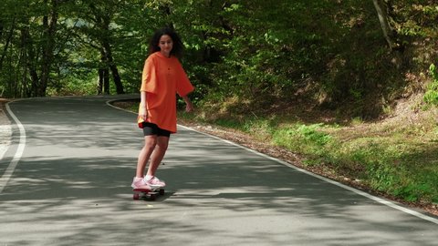 happy teenager girl is skateboarding at summer holidays and weekend, young woman is riding on skateboard, sport hobby and entertainment