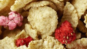 Corn flakes with strawberry in a bowl without milk rotation. 4K. macro close up