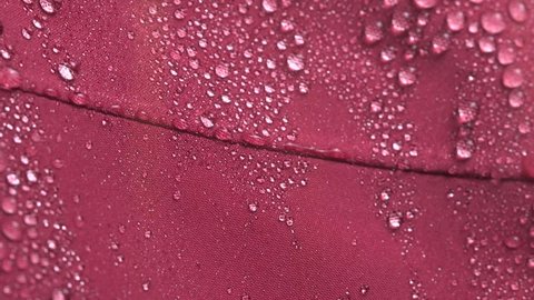Slow motion close-up of falling water drops on waterproof membrane Gore-Tex cloth.