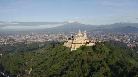 San Andres Cholula, Puebla, Mexico. July 02 of 2019. Our Lady of Remedies Church on the Great Pyramid of Cholula with Popocatepetl and Iztaccihuatl active volcanoes in the background. 