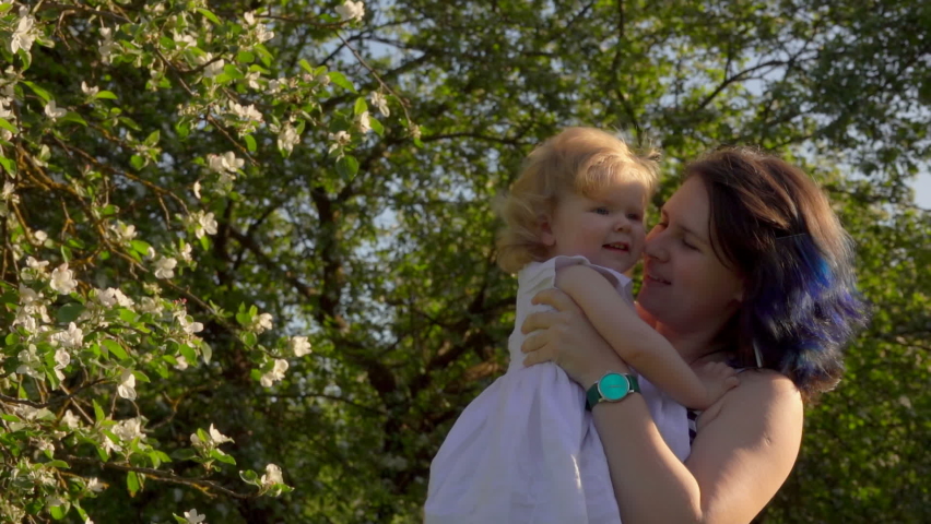 Mom is throwing up and rotating her little adorable daughter in a white dress