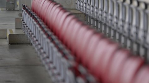 Row of empty red fold out seats in football rugby stadium. Shallow focus
