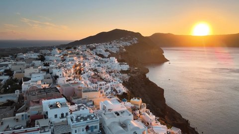 Cinematic aerial shot of famous Oia village in Santorini at sunrise in Greece