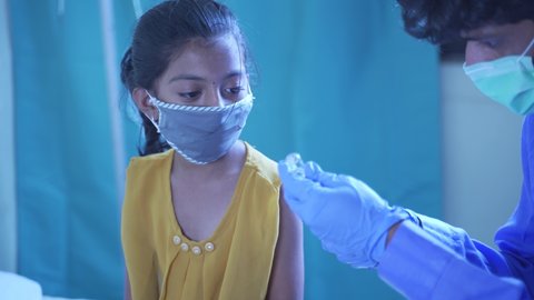 Concept of Covid-19 coronavirus vaccination for children - Young girl kid getting jab or vaccinated to against covid at hospital.