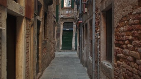 Slow steady pov walk in narrow alley surrounded by old historic buildings during daytime. Venice,Italy.