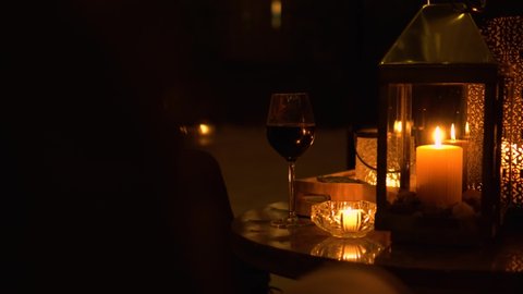A woman drinking wine in candlelight at the patio while it snows outside during quarantine