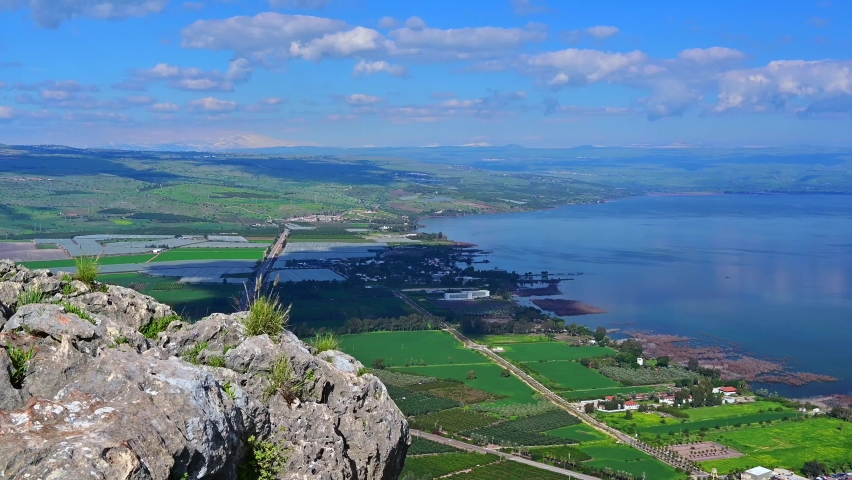 Beautiful 4K video of the Sea of Galilee from the cliff of Mount Arbel National Park and Nature Reserve, with clouds in the sky and snow-capped Mt Hermon in the distance; Lower Galilee, Israel