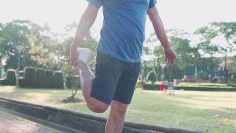 asian man doing standing leg stretching at public park before exercise, joint ligament bone problem, holding up leg, injury prevention, active lifestyle, warm up before running, burning calories	
