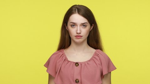 You are crazy, out of mind! Annoyed girl in summer dress pointing at camera and showing stupid gesture, blaming some idiot, accusing cuckoo mind. Indoor studio shot isolated on yellow background.