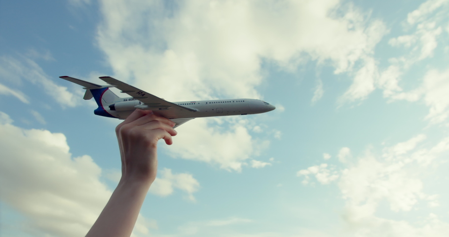 A little boy's hand holds a believable airplane model. It seems to fly over the city against the background of a beautiful sky with clouds, houses, a large temple and trees. The toy is well made Royalty-Free Stock Footage #1073212820