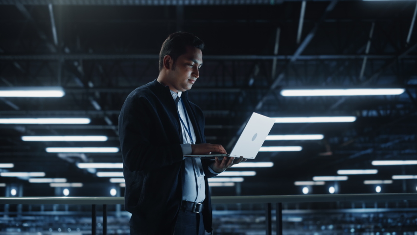 Portrait of IT Specialist Uses Laptop in Data Center. Server Farm Cloud Computing Facility with Male Maintenance Administrator Working. Cyber Security and Network Protection. Wide Medium Tracking Shot Royalty-Free Stock Footage #1073218847