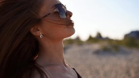 Young attractive playful blonde woman in swimsuit and sunglasses walking on a sunny tropical beach. Long hair pretty girl in bikini enjoying the walk on the sandy sea shore in slow motion. Sun flares. - Powered by Shutterstock - Get 15% off with code: PIKWIZARD15