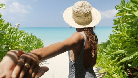 Slow motion: Young couple holding hands on tropical vacation. Female holding companion hand follow me to concept. Woman leading the way on idyllic tropical beach 