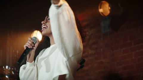 CU Portrait of Black African American young female comedian performing her stand-up monologue on a stage of a small venue. Shot with ARRI Alexa Mini LF with 2x anamorphic lens