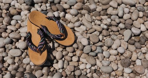 Flip-flops on pebbles beach washed by crystal seawater and foam, travel concept