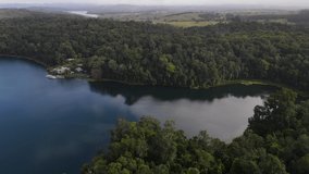 Aerial drone video revealing a large volcanic crater lake fringed with a lush tropical rainforest