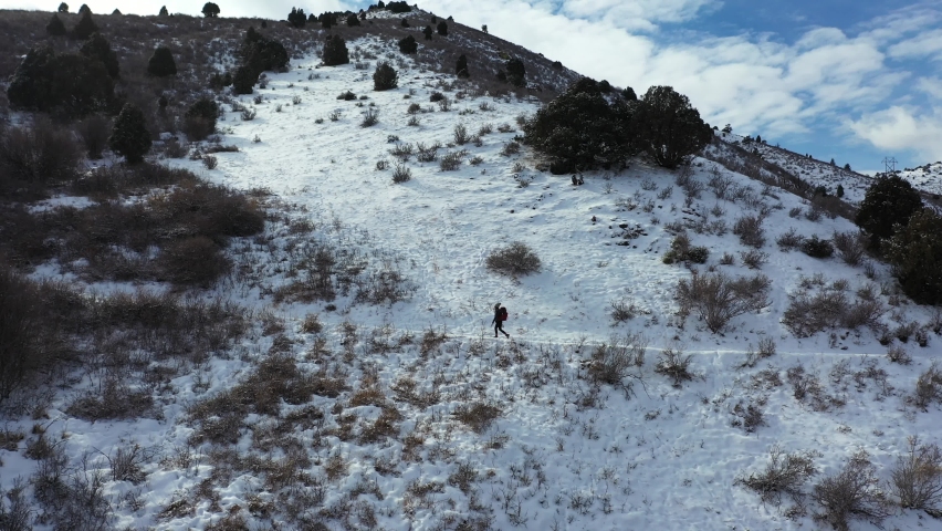 Aerial View of Solo Hiker Walking on Snow Capped Hillside. Winter Landscape and Lonely Female on Hiking Trail, Drone Shot