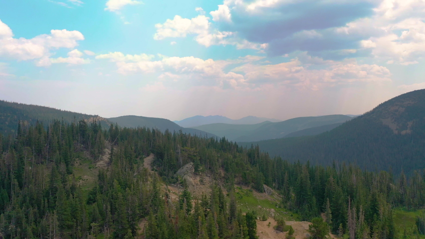 Aerial Drone Reveal of Nederland Colorado Mountain Views and Clouds Casting Shadows Over Lush Pine Tree Forest during Summer in the Rocky Mountains