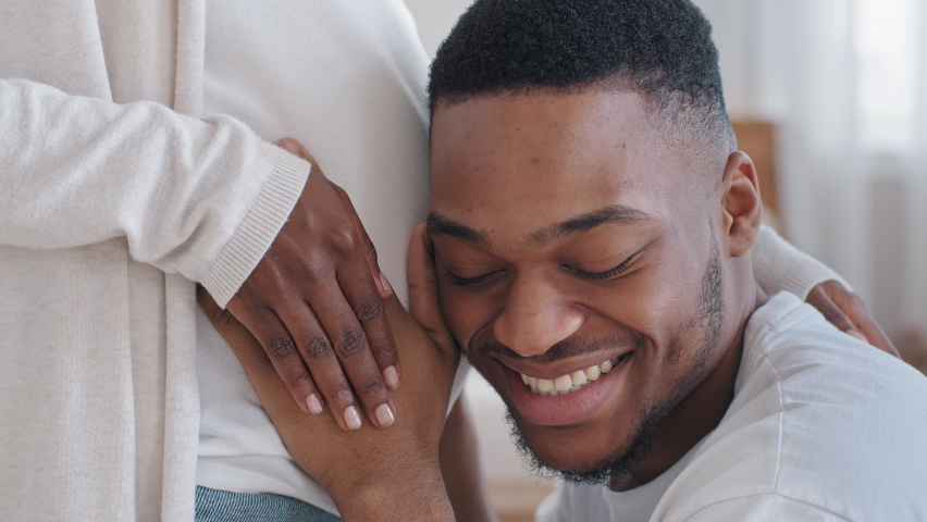 Close-up male head loving caring afro american black ethnic husband father hugs embraces touching listening pregnant female belly enjoying sounds of unborn future baby feeling happy, pregnancy concept Royalty-Free Stock Footage #1073251397