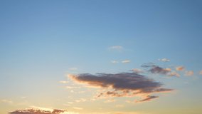 Video time lapse of beautiful peaceful cloudy sunset clear blue heaven. White and orange sunny soft clouds moving slowly in evening golden sky. Panoramic natural background