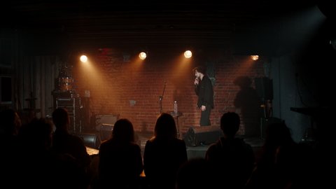 DOLLY Young Caucasian male comedian entering stage and greeting audience, performing his stand-up monologue inside a small venue. Shot with ARRI Alexa Mini LF with 2x anamorphic lens