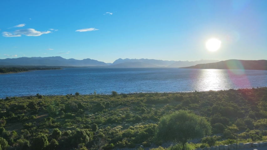 Aerial view of the Nahuel Huapi lake and the radiant sun before sunset. Bariloche, Argentina.