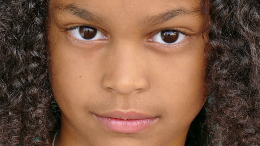 Portrait of happy children with emotions and feelings. Black young girl smiling, looking at camera with joyful and funny smile, female child with glad expression on face. Extreme close-up