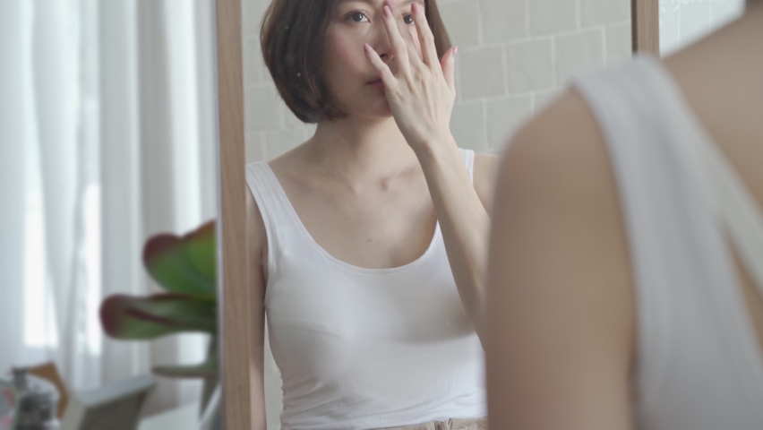 attractive beautiful short hair asian woman worry looking into mirror for face skin care condition. Frustrated Young female Examining Her Face While Looking At The Mirror in bathroom. annoy facial age Royalty-Free Stock Footage #1073270594