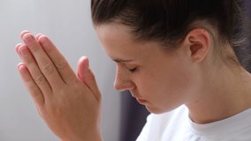 Close up side view of hopeful young woman 20s holds hands in prayer to god. Beautiful peaceful caucasian lady meditating, praying for health, mindfulness and success. Improve mental health concept - Powered by Shutterstock - Get 15% off with code: PIKWIZARD15