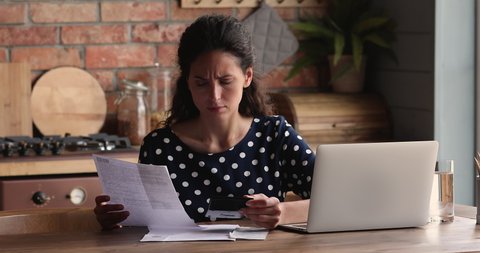 Confused young woman recalculating utility bills, feeling stressed of made mistake, wrong information or lack of money. Unhappy hispanic lady managing monthly budget, thinking of financial problems.