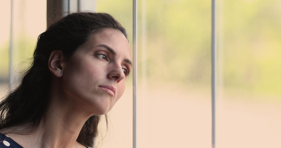 Close up head shot unhappy young hispanic latin caucasian woman looking out of window, feeling bored alone at home, suffering from solitude loneliness indoors, having psychological problems. | Shutterstock HD Video #1073278103