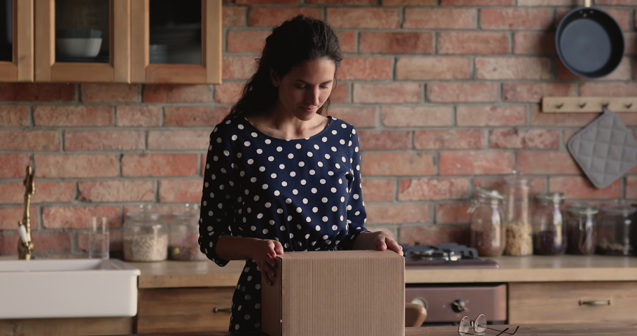 Confused young hispanic woman unwrapping cardboard box, feeling disappointed with received wrong or damaged item, displeased with negative online shopping experience or unreliable delivery service. Royalty-Free Stock Footage #1073278265