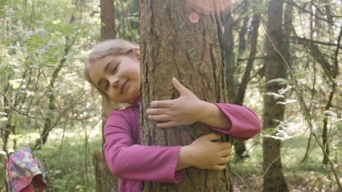 Contented Little Girl Hugging Large Tree With Blissful Expression of Nature Conservation. Harmony Calm Relaxation. Save Earth Green Planet. Child Girl Hugging Tree Trunk in Park, Nature Life Love.