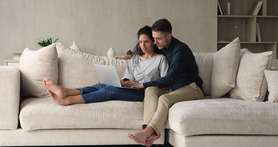 Couple sit on couch using laptop buy goods services on internet, planning vacation buy tickets booking hotels, enjoy easy comfort e-banking app. Comfort usage of modern tech e-commerce clients concept | Shutterstock HD Video #1073296604