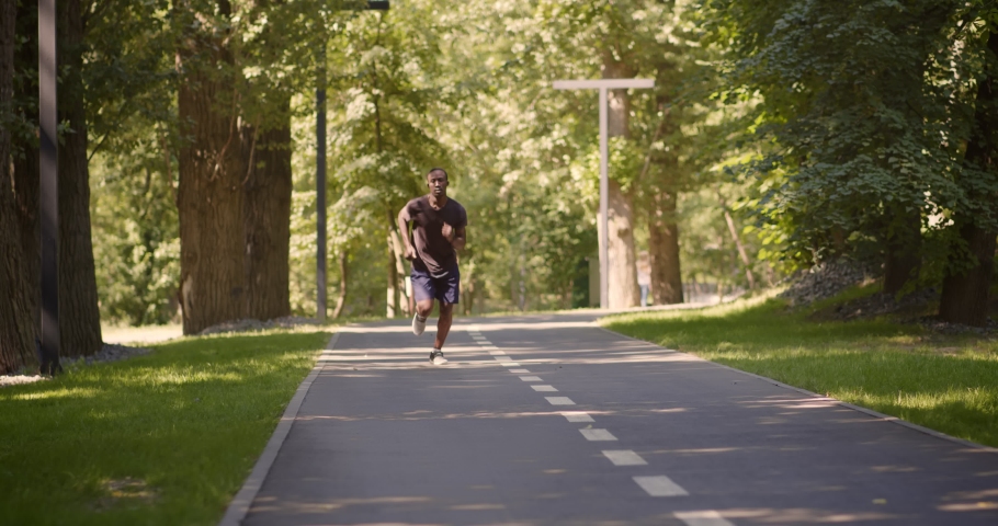 Sport trauma. Young active african american man jogging in park, spraining his foot, suffering from acute leg pain during outdoor training, slow motion Royalty-Free Stock Footage #1073297267