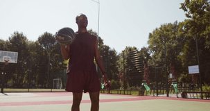 Basketball workout. Young african american guy in uniform playing streetball at outdoor court, training alone, slow motion