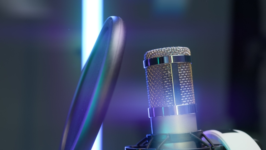Close-up professional microphone for dubbing and singing in recording studio in rays of colorful floodlights. Studio recording, professional microphone in recording studio, close-up, podcast concept. Royalty-Free Stock Footage #1073299241