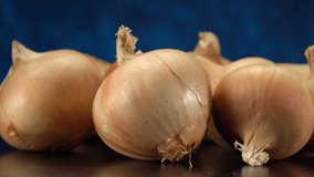 Video close-up of white onion bulbs, on a dark background.