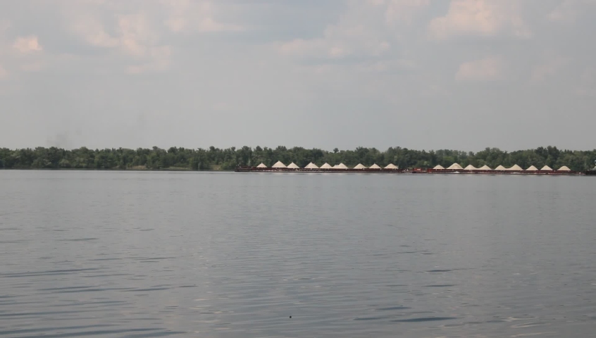 The tug pushes the barge along river.