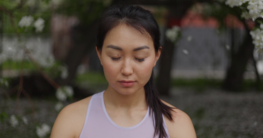 Woman doing yoga pose on the background of a blooming apple tree