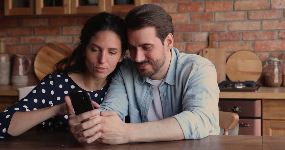 Overjoyed young loving family couple looking at smartphone screen, getting message with good news, celebrating online lottery gambling giveaway win, receiving low price discount shopping promo code. Royalty-Free Stock Footage #1073311778