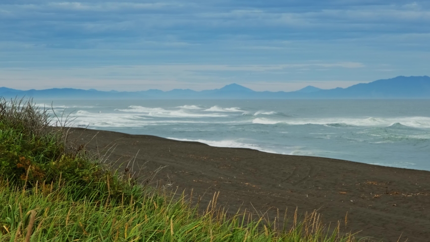Khalaktyrsky beach with black sand and waves of Pacific ocean, Kamchatka peninsula, Russia, 4k