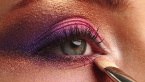 Make-up artist applies makeup to the upper eyelid, close-up.  Makeup artist applies a bright eye shadow with a makeup brush.Tutorial master class of professional makeup. Slow motion cinematic shoot. 