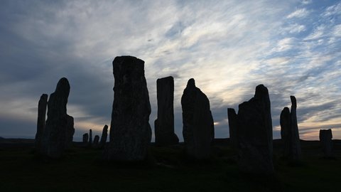 4k time lapse of cloud and light movement over Callanish Stones at sunset. Stones in silhouette. No people. Famous prehistoric standing stones, Isle of Lewis, Outer Hebrides, Scotland.